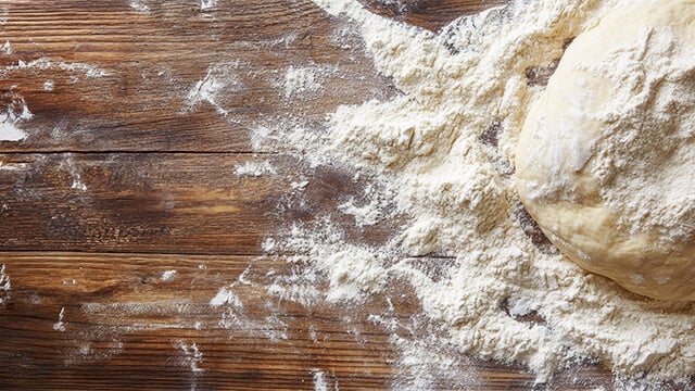Dough and flour on wooden backgound